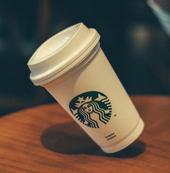 A close-up image featuring the Starbucks logo on a paper cup, showcasing the iconic green emblem and symbolizing the brand's commitment to sustainability and quality.